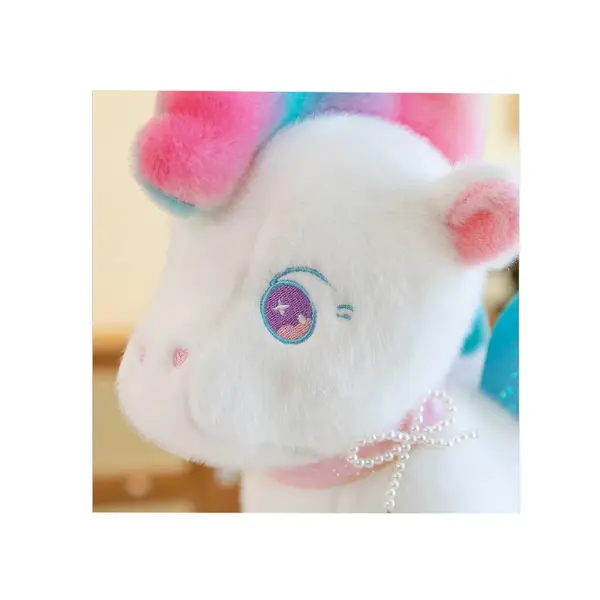 Detaliu cap unicorn din pluș cu broderie